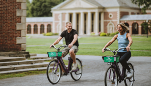 Two guests riding bikes near the Gideon Putnam in summer